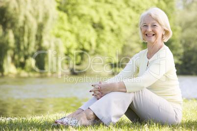 Woman outdoors at park by lake smiling