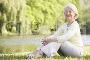 Woman outdoors at park by lake smiling