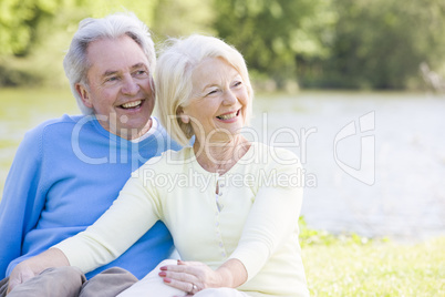 Couple outdoors at park by lake smiling