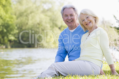 Couple outdoors at park by lake smiling