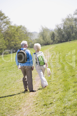 Couple walking on path in park holding hands