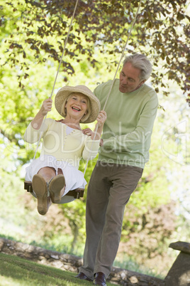 Couple outdoors with tree swing smiling