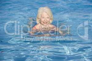 Woman swimming in outdoor pool smiling