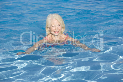 Woman swimming in outdoor pool smiling