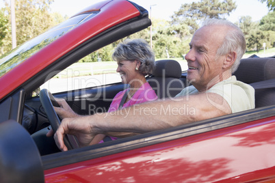 Couple in convertible car smiling