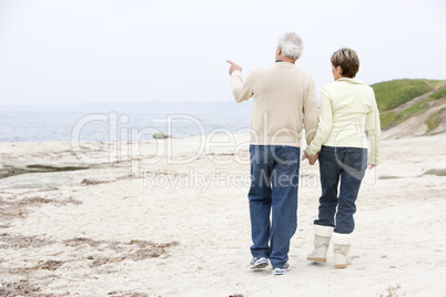 Couple at the beach holding hands and pointing