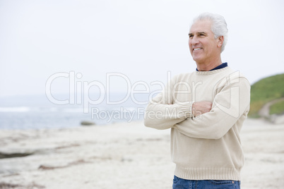 Man at the beach with arms crossed smiling