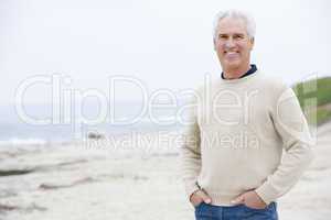 Man at the beach with hands in pockets smiling