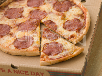 Pepperoni Pizza in a Take Away Box with a Cut Slice