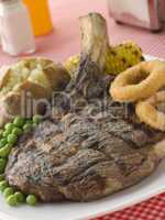 Ribeye Steak on the bone with Baked Potato Peas Onion Rings and
