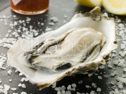 Opened Rock Oyster with Hot Chilli Sauce Lemon and Sea Salt