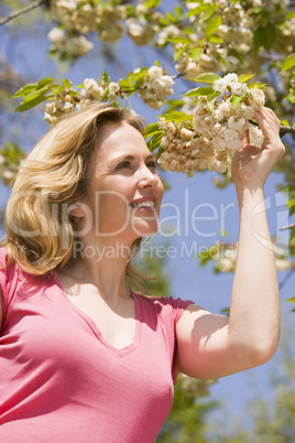 Woman standing outdoors holding blossom smiling