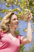 Woman standing outdoors holding blossom smiling