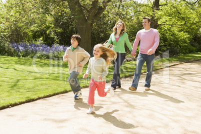 Family running on path holding hands smiling