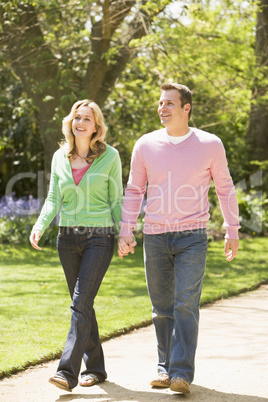 Couple walking on path holding hands smiling