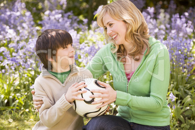 Mother and son outdoors holding ball smiling