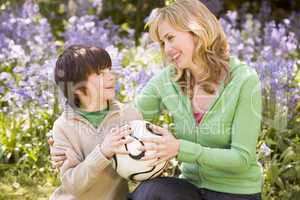 Mother and son outdoors holding ball smiling