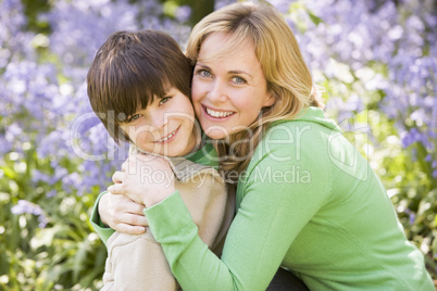 Mother and son outdoors embracing and smiling