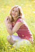 Woman outdoors holding flower smiling