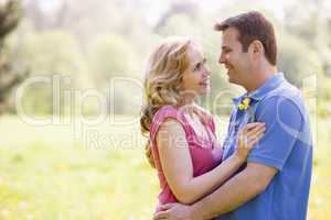 Couple embracing outdoors holding flower smiling