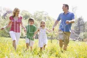 Family walking outdoors holding hands smiling