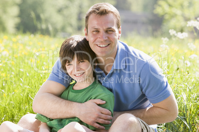 Father and son sitting outdoors smiling