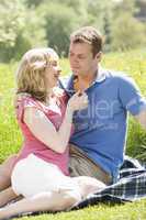 Couple sitting outdoors holding flower smiling