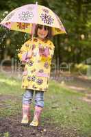 Young girl outdoors in rain with umbrella smiling