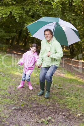Father and daughter outdoors with umbrella smiling