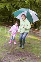 Father and daughter outdoors with umbrella smiling