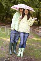Couple outdoors in rain with umbrella smiling