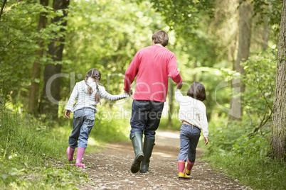 Father and daughters walking on path holding hands smiling