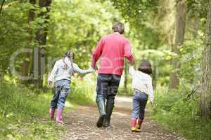 Father and daughters walking on path holding hands smiling