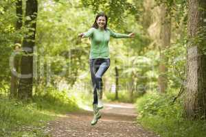 Woman jumping on path smiling