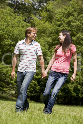 Couple walking outdoors holding hands smiling