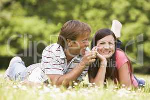 Couple lying outdoors with flower smiling