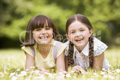 Two sisters lying outdoors smiling