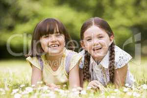 Two sisters lying outdoors smiling