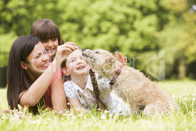 Mother and daughters in park with dog smiling