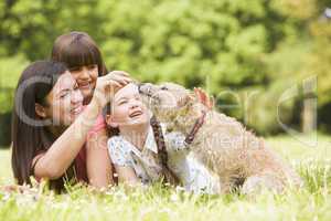 Mother and daughters in park with dog smiling