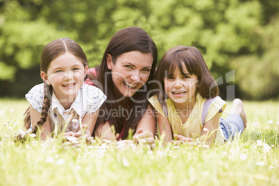 Mother and daughters lying outdoors with flower smiling