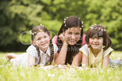 Mother and daughters lying outdoors with flowers smiling
