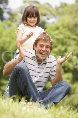 Father and daughter sitting outdoors with flowers smiling