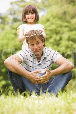 Father and daughter sitting outdoors with flowers smiling