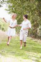 Couple running on path holding hands and smiling