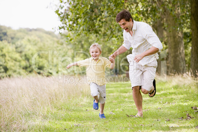 Father and son running on path holding hands smiling