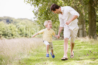 Father and son running on path holding hands smiling