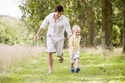 Father and son running on path smiling