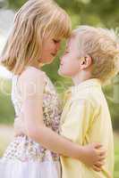 Two young children hugging outdoors