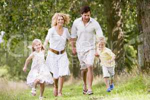 Family running on path holding hands smiling